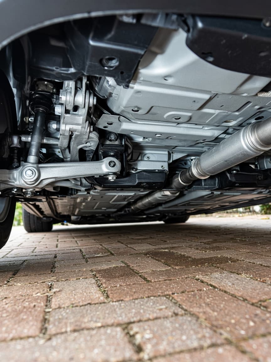 Clean underside of a car above a brick driveway