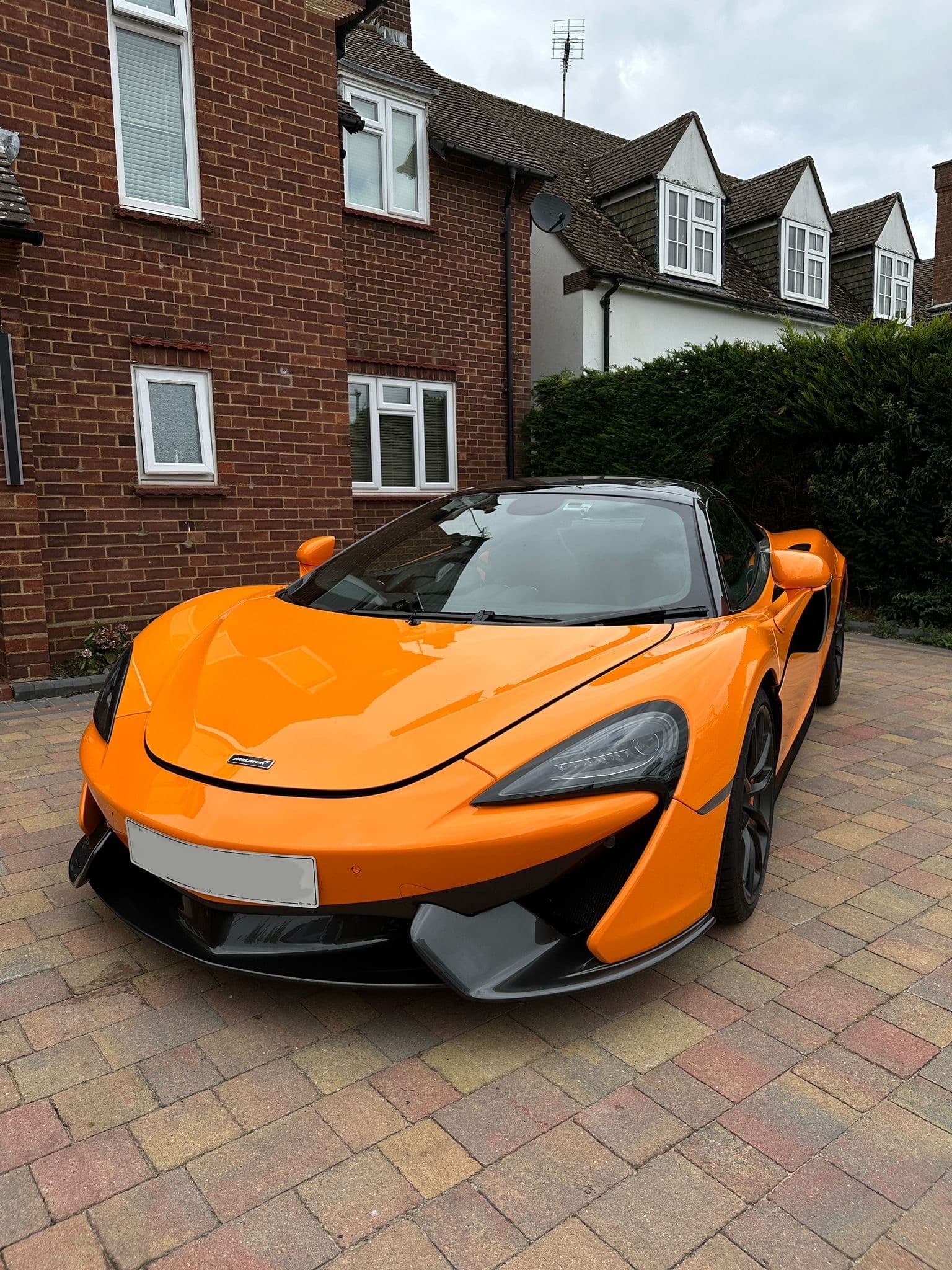 Orange McLaren on a brick driveway
